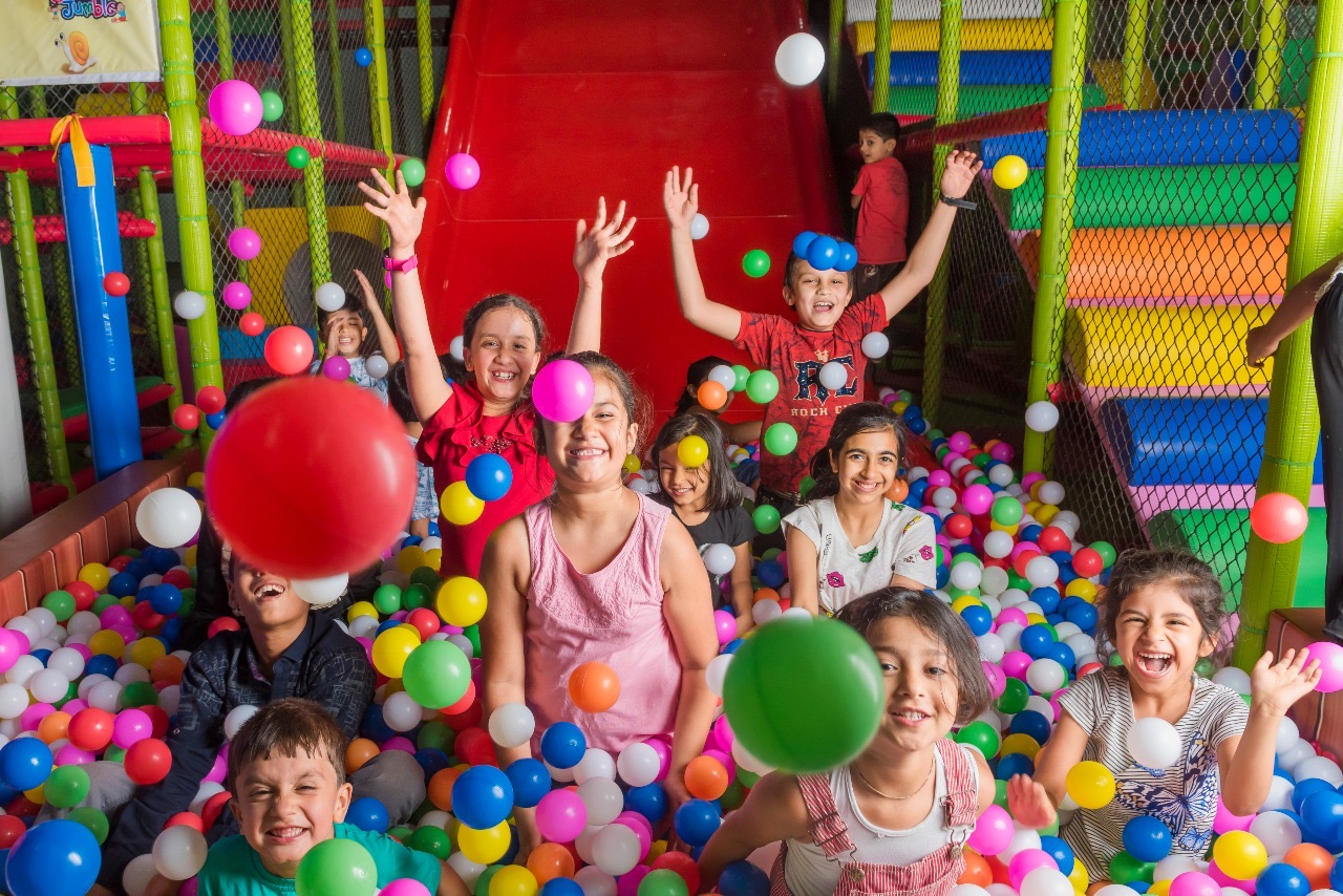 Kids laughing and throwing colourful balls in the Bumble Jumble ball pit